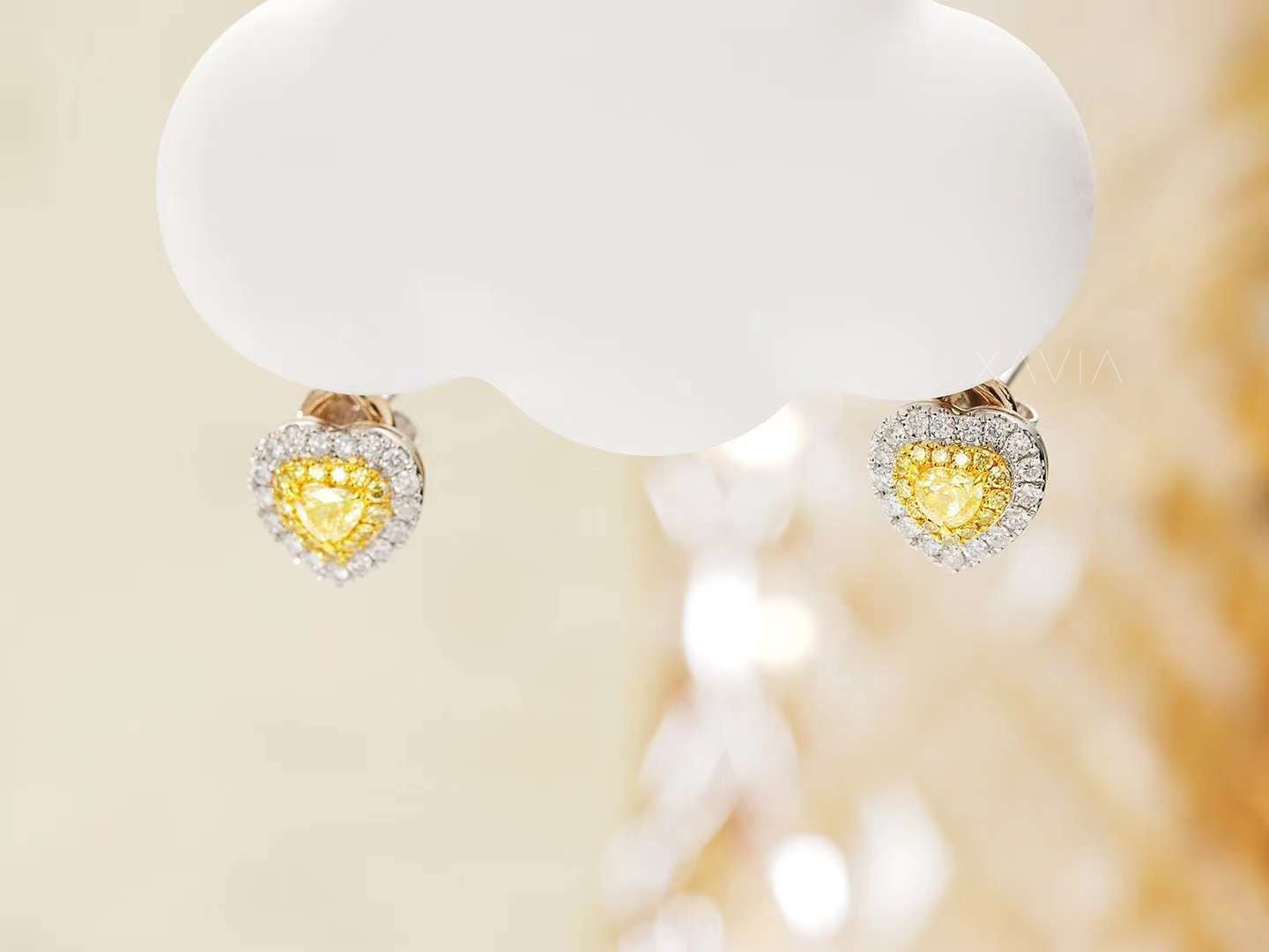 Yellow heart lab diamond halo earrings hanging on display